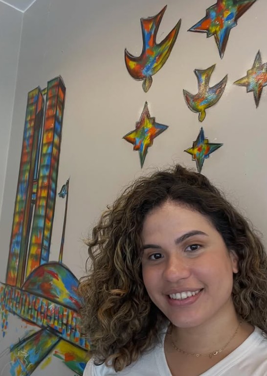 Pâmela em Brasília, diante de um mural do Congresso Nacional